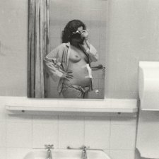 3/4 length self portrait, camera held to face, pyjama top open, 1979 Carol Jerrems