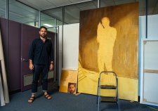 Christopher Bassi standing in an empty office next to a large yellow painting