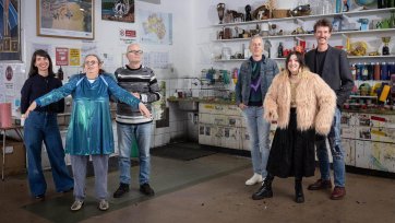 Two grounps of three people standing in a studio with walls and shelves filled with artworks