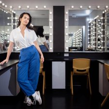 Amrita Hepi standing in front of a dressing room mirror surrounded by lights