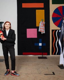 Sally Smart standing in her wooden floored studio holding a puppet